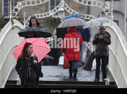 Persone attraversano il Ha'penny Bridge in un giorno di pioggia a Dublino. Foto Stock
