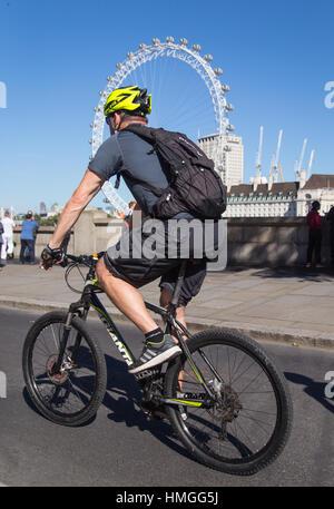 Di mezza età ciclista maschio a cavallo su est-ovest il superhighway di ciclo con il London Eye in background su un soleggiato fine settimana estivo nel centro di Londra Foto Stock