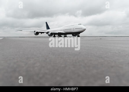 Basso angolo di vista grande aereo di linea di passeggeri piano a getto sulla pista di rullaggio o pista Foto Stock