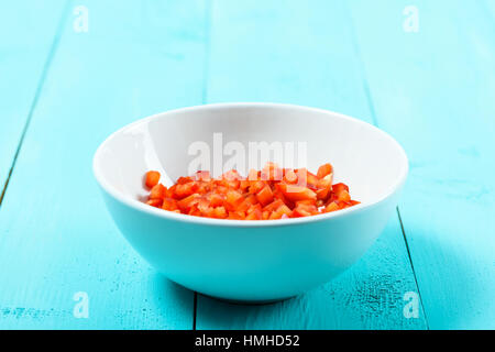 Rosso tritato Capsicum in bianco ciotola sul tavolo Turchese Foto Stock