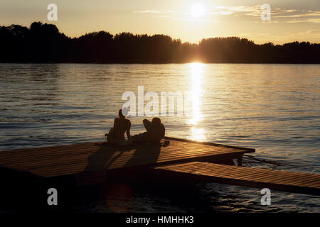 Younmg giovane rilassante su un molo presso il fiume Danubio al tramonto, Vac, Pest County, Ungheria Foto Stock