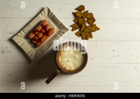 Boccale di birra, salsicce e pane secco su sfondo di legno Foto Stock