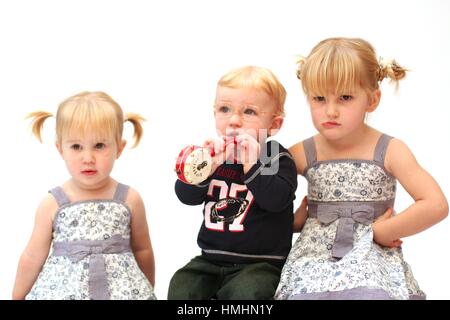 Blonde bambini kids family photoshoot giocare insieme, un bambino guardando arrabbiato con mani sui fianchi cross bambino, scontroso concetto fornendo fuori, alimentato fino Foto Stock