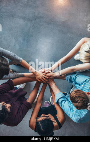 Vista Top Shot della pila di mani. I giovani studenti del college di mettere le mani sulla parte superiore di ogni altro che simboleggiano l unità e il lavoro di squadra. Foto Stock