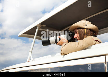 Ragazza in piedi in jeep safari a tetto aperto con macchina fotografica Foto Stock