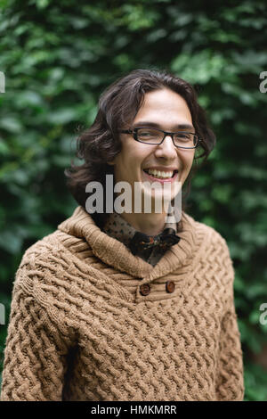 Giovani multirazziale uomo sorridente e in piedi contro lo sfondo di colore verde, guardando la fotocamera Foto Stock