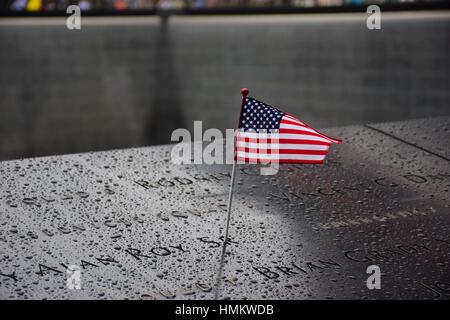 Il memorial a Ground Zero Manhattan per attentato terroristico dell 11 settembre con una bandiera americana accanto ai nomi delle vittime incisi Foto Stock