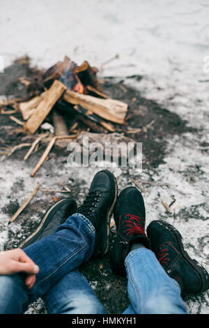 Ragazzo e ragazza piedi caldi nei pressi di un incendio Foto Stock