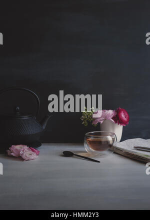 Ancora la vita di rosa ranunculus in bianco piccolo vaso in ceramica con vetro tazzina e cucchiaio, chiave di basso, Moody, semplice, in stile Foto Stock