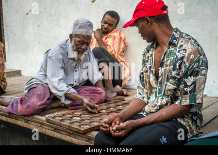 Gli uomini gioca bao, gioco della famiglia dei mancala, su una strada di Stone Town Zanzibar, Tanzania Foto Stock