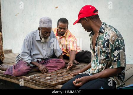 Gli uomini gioca bao, gioco della famiglia dei mancala, su una strada di Stone Town Zanzibar, Tanzania Foto Stock