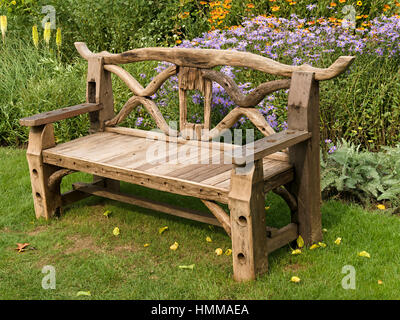 Ornati, rustica e giardino in legno sedile unico composto da materiali riciclati di parti in legno nella parte anteriore di letti inferiori, Coton Manor Gardens, Northamptonshire, England, Regno Unito Foto Stock