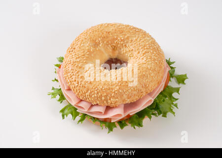 Bagel sandwich con prosciutto su sfondo bianco Foto Stock