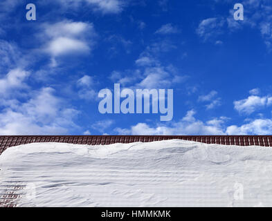 Tetto nella neve e cielo blu con nuvole in sun giornata invernale Foto Stock