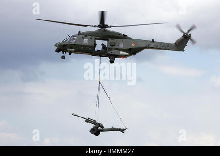 BEAUVECHAIN, Belgio - 20 Maggio 2015: belga esercito elicottero NH90 trasporta un pezzo di artiglieria Foto Stock