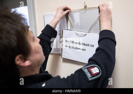 Amburgo, Germania. 10 Febbraio, 2017. Un funzionario del tribunale si blocca un avviso con le parole 'ingresso vietato al pubblico" in lingua tedesca in un tribunale di Amburgo, Germania, 10 febbraio 2017. La corte è udito un caso in questione con la copertura di notizie delle condizioni di salute della Formula 1 pro Michael Schumacher. Il processo si è aperto con l'interrogatorio di un testimone impiegato come deputy editor di un tabloid tedesco chiamato "Bunte'. La carta ha segnalato la Schumacher era in grado di camminare di nuovo nel dicembre 2015. Foto: Christian Charisius/dpa/Alamy Live News Foto Stock