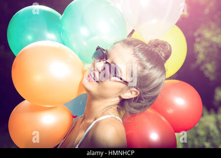 Ragazza con palloncini in natura rendendo le espressioni del viso Foto Stock