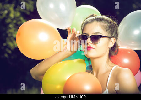 Ragazza con palloncini in natura rendendo le espressioni del viso Foto Stock