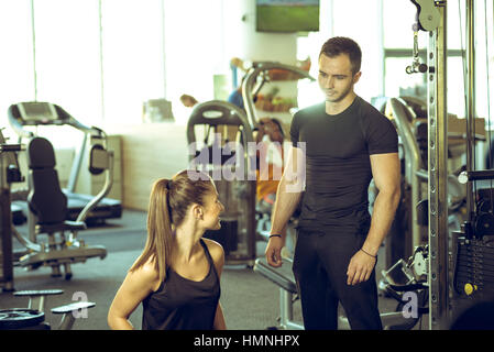 Giovane maschio personal fitness trainer parla ai suoi client femmina e dando i suoi consigli per la motivazione. Foto Stock