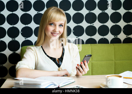 Ragazza seduta in cafe contiene uno smartphone Foto Stock