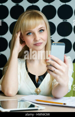 Ragazza seduta in cafe contiene uno smartphone Foto Stock