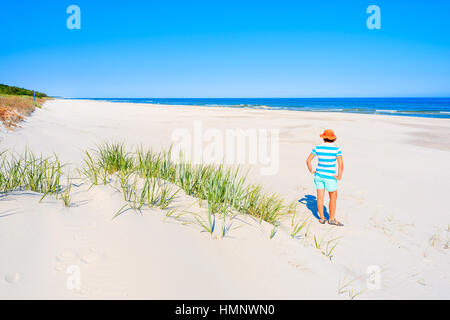 Giovane donna in piedi sulla sabbia bianca e guardando alla bellissima spiaggia, Mar Baltico, Polonia Foto Stock