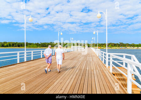 Coppia di uomini anziani camminando sul molo di legno in Jurata cittadina sulla costa del Mar Baltico della Polonia Foto Stock