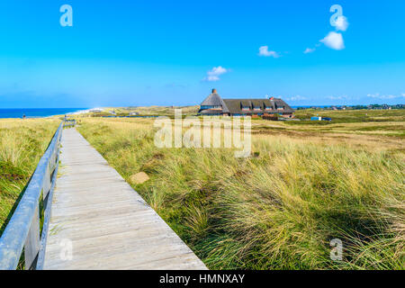 Percorso a piedi lungo una costa di Isola di Sylt e Frisone tipici guest house in background, Germania Foto Stock