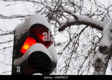 In prossimità della fermata semaforo rosso coperto di neve in inverno con alberi in background Foto Stock