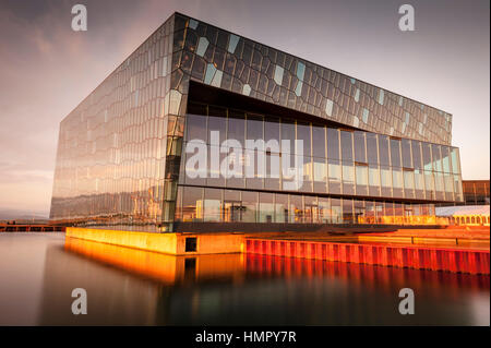 Il sole di mezzanotte si riflette nella Sala dei Concerti e del Centro Congressi di Harpa, il Teatro dell'Opera, Reykjavik, Islanda, vista sul mare al tramonto. Foto Stock