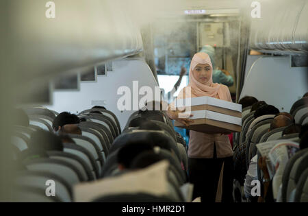 Un assistente di volo Royal Brunei femmina trasporta i beni di un passeggero attraverso l'aereo Airbus A320 all'aeroporto internazionale di Bandar a Darussalam, Bandar seri Begawan, Brunei. © Time-Snap Foto Stock