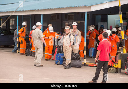 I lavoratori petroliferi in tute arancioni sono visti dopo il loro trasferimento dalle piattaforme offshore di perforazione petrolifera tramite navi di supporto al porto vicino a Kuala Belait, Brunei. © Time-Snap Foto Stock