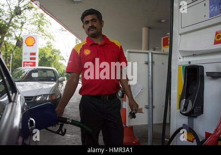 Un addetto indiano alla pompa sta riempiendo un'auto con benzina presso un distributore di benzina Shell nella regione di Seria, Brunei. © Time-Snap Foto Stock