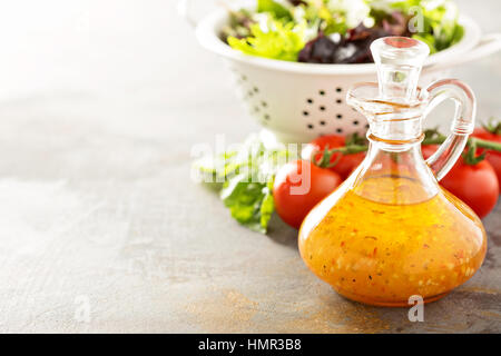 Italian vinaigrette dressing in una bottiglia vintage con verdure fresche sul tavolo Foto Stock