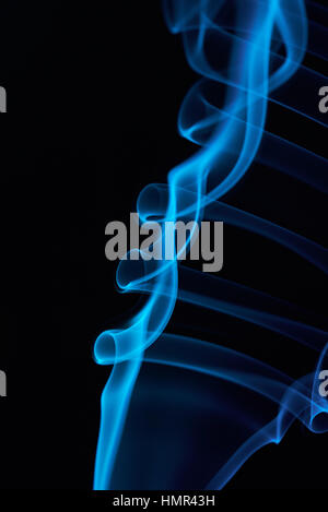 Close up blu fumo ricci linee su sfondo nero Foto Stock