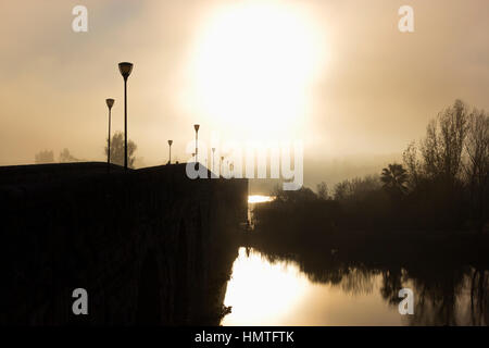 Merida, Estremadura, Spagna. Misty tramonto sopra il ponte romano. Foto Stock