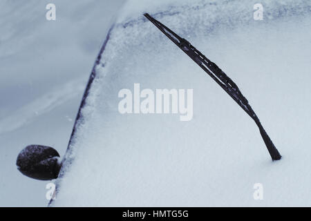 Close up di un nero sollevato auto tergivetro del parabrezza ricoperta di neve in inverno il tempo su una strada di città Foto Stock