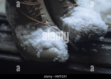 Vista superiore in prossimità di una coppia di pelle marrone vintage scarpe dalla casa di legno aperto della porta d'ingresso coperto di neve in inverno Foto Stock