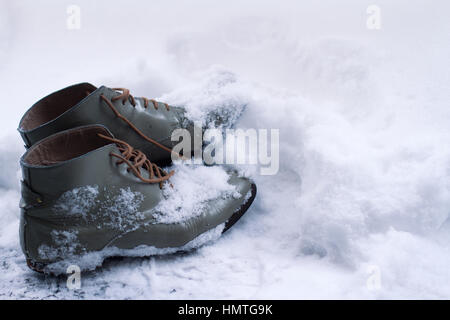 Vista laterale ravvicinata di un grigio di una coppia di marrone vintage scarpe in pelle ricoperta di neve in inverno Foto Stock