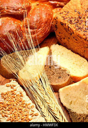 Pane fresco, spighe di grano, grani di grano sullo sfondo di legno Foto Stock