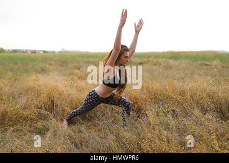 Giovane femmina istruttore di fitness esegue il warm-up, esercizi di stretching e azienda si concentra sulla corretta esecuzione pone, fotografata per la pubblicità di Foto Stock