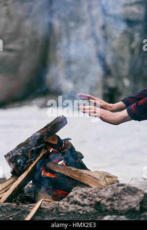 La ragazza si scalda le mani in prossimità di un fuoco in inverno Foto Stock