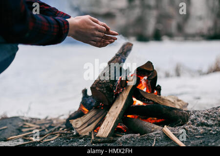 La ragazza si scalda le mani in prossimità di un fuoco in inverno Foto Stock