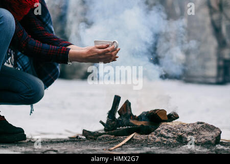 La ragazza si scalda le mani in prossimità di un fuoco in inverno Foto Stock