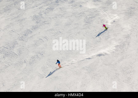 Due sciatori su una ripida pista nera con sentieri di polvere di neve dietro di loro. Foto Stock