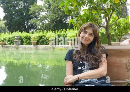 Bella ragazza con i capelli lunghi in posa in prossimità di un lago artificiale e un albero di limone Foto Stock