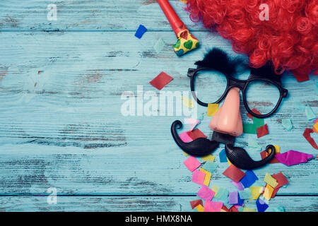 Una parrucca rosso, una coppia di finti occhiali neri con le sopracciglia,  un rosso clown naso e un baffi formando il volto di un uomo su un rustico  blu superficie in legno