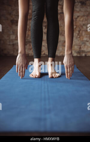 Primo piano della slim giovane donna fitness a piedi nudi e lo stiramento del tappetino Foto Stock