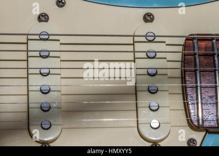 Primo piano di una chitarra elettrica Fender Stratocaster che mostra corde, pickup a bobina singola e pezzi di palo e una piastra bianca Foto Stock