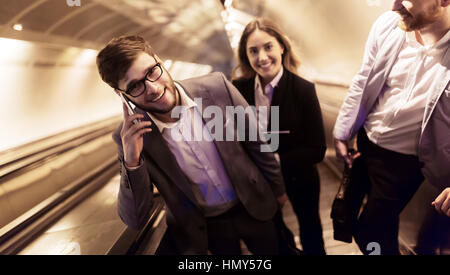 I suoi collaboratori utilizzando le scale della metropolitana insieme per ottenere la metropolitana Foto Stock